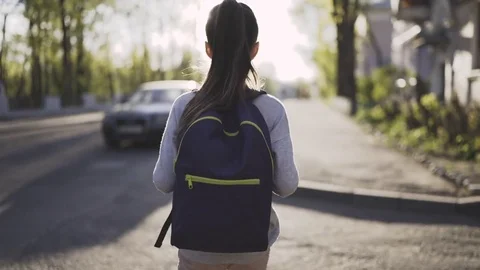 Child girl is walking with a school bag in sunny day Stock Footage