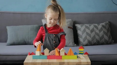 Child with glasses collects a multi-colored constructor at a table Stock Footage 128663957