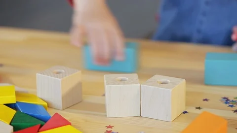 A child with glasses collects a multi-colored constructor Stock Footage 129341961