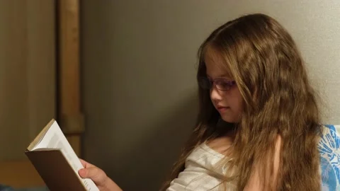 Child in glasses read book before bedtime in bed in dark bedroom with night lamp Stock Footage 200376797