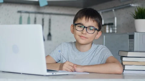 The child in glasses teaches lessons while at home sitting in the kitchen at the Stock Footage 127931918