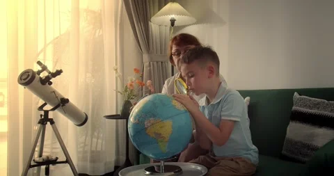 Child with grandmother is studying while sitting at home in rays sunset in room Stock Footage 289027313