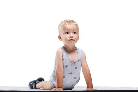 Child in a gray star-pattern outfit plays on a mat while looking up with Stock Photos