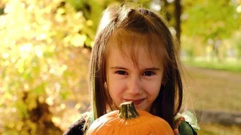 A child, grimacing, hides behind a pumpkin with a sinister face Stock Footage 160991359