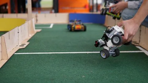Child guiding small programmable robot car across indoor track during hands on Stock Photos
