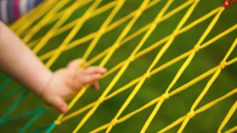 Child hand climbs the net of a summer hammock. Close-up Vídeo Stock 243939107