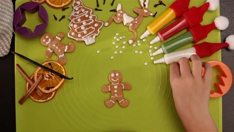Child hand decorates gingerbread christmas cookie with sugar pearls Video stock 80299152