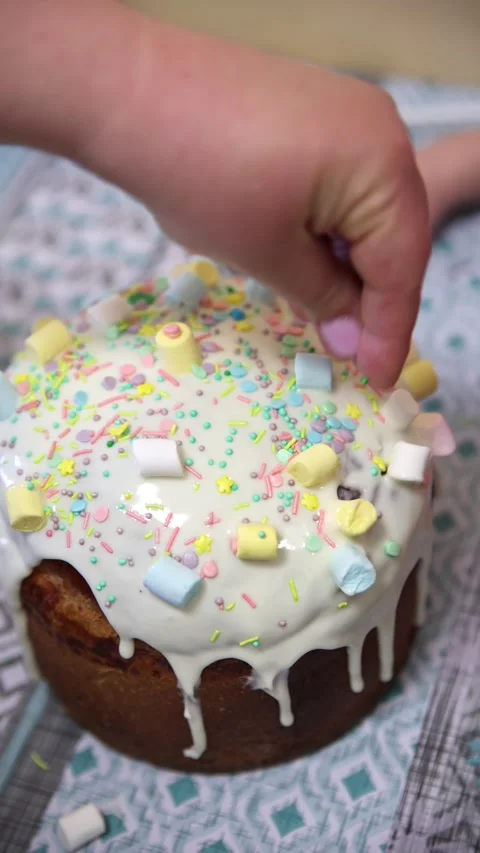 Child Hand Decorating Easter Kulich with Colorful Sprinkles and Marshmallows Vídeo Stock 333010260