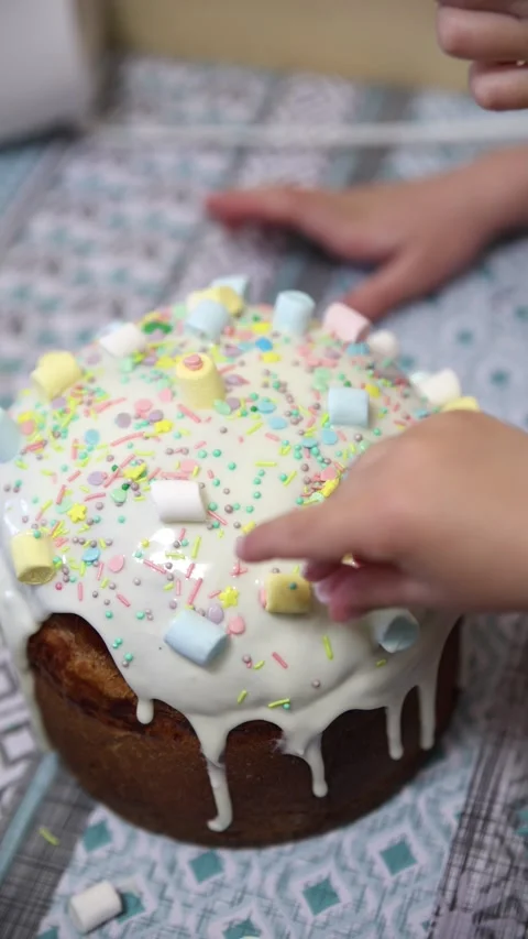 Child Hand Decorating Easter Kulich with Colorful Sprinkles and Marshmallows Stock Footage 333010262