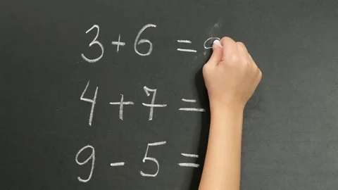 Child hand doing simple math exercises on black chalk board, close up Stock Footage 125037893