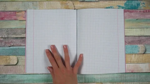 Child hand opens pink notebook in cell. Blank paper sheet for math Stock Footage 243663680