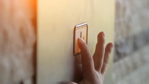 Child hand presses on button with arrow in modern lift Stock Photos