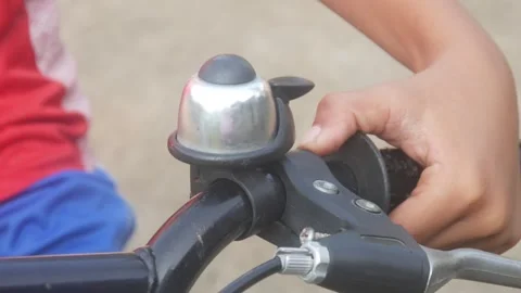 A child hand is ringing the bell on the handlebars of a bicycle outdoors. Stock Footage 332866633