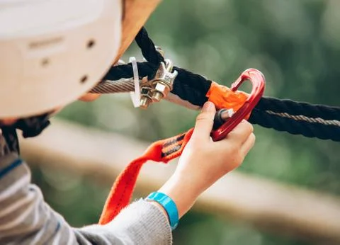 Child hand with safety spring hook in the rope park attraction Stock Photos