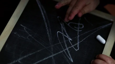 Child hand scribbling with white chalk on a black retro slate board, Stock Footage 107143300