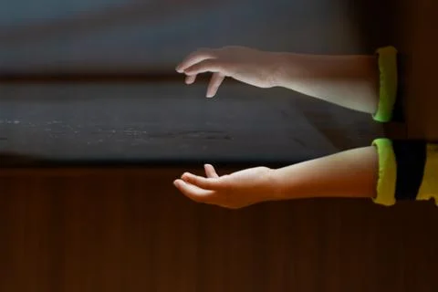 Child hand touching an illuminated interactive surface with reflection repr.. 库存照片