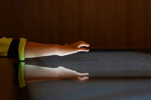 Child hand touching an illuminated interactive surface with reflection repr.. Stock Photos