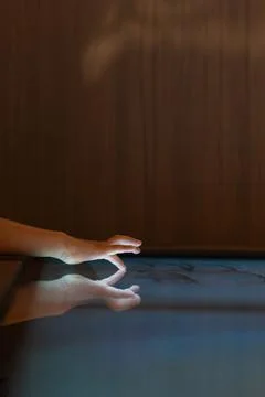 Child hand touching an illuminated interactive surface with reflection repr.. Stock Photos