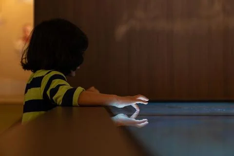 Child hand touching an illuminated interactive surface with reflection repr.. Photos