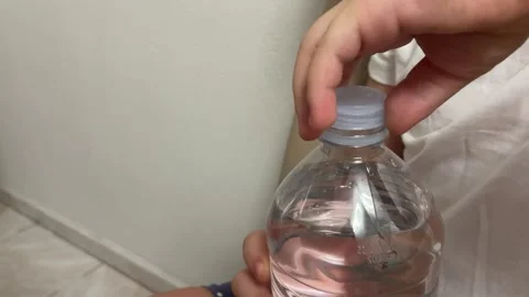 Child hand unscrewing cap of clear plastic water bottle Stock Footage 339806143