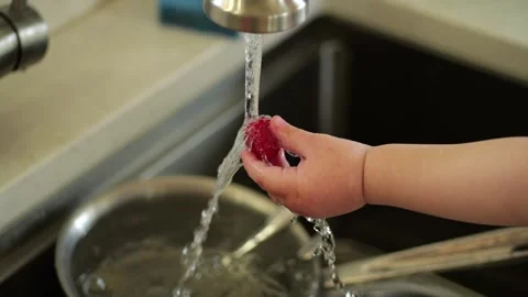 Child hand washing a fresh raspberry under tap water Video stock 328669394