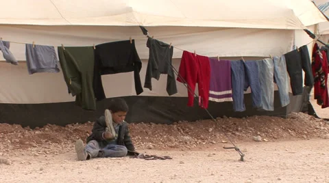 Child handling a shoe in Zaatari Refugee Camp Stock Footage 35790075