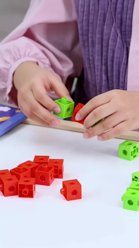 Child Hands Connecting Red and Green Math Manipulative Cubes on Table Stock Footage 325701005