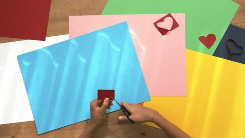 Child hands cutting colored paper with scissors. Top down view to table with Stock Footage 132942863
