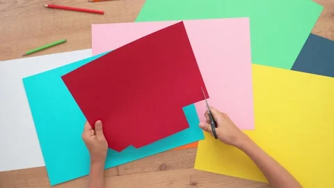 Child hands cutting colored paper with scissors. Top down view to table with Stock Footage 132945677