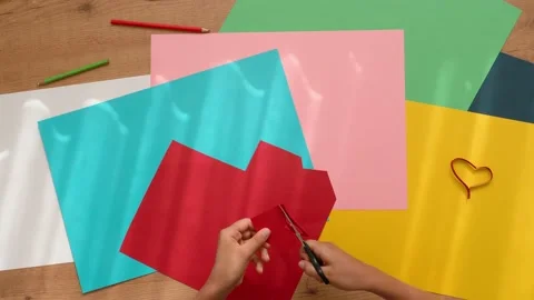 Child hands cutting colored paper with scissors. Top down view to table with Stock Footage 134587344