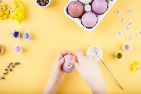 Child hands decorate Easter eggs on yellow background. Happy easter concept. Stock Photos