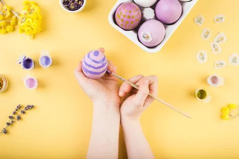 Child hands decorate Easter eggs on yellow background. Happy easter concept. Stock Photos