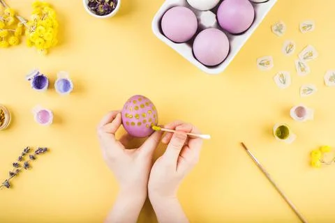 Child hands decorate Easter eggs on yellow background. Happy easter concept. Stock-Fotos