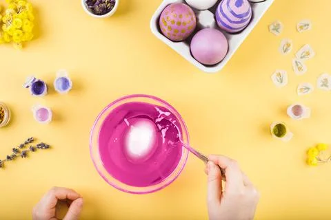 Child hands decorate Easter eggs on yellow background. Happy easter concept. Stock Photos