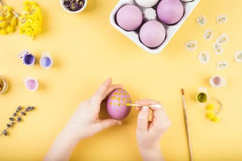 Child hands decorate Easter eggs on yellow background. Happy easter concept. Stock Photos