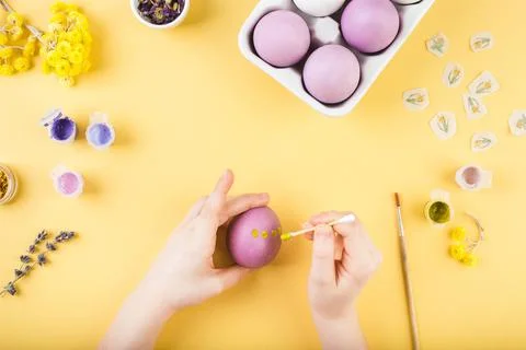 Child hands decorate Easter eggs on yellow background. Happy easter concept. Stock Photos