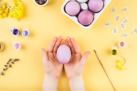 Child hands decorate Easter eggs on yellow background. Happy easter concept. Stock Photos