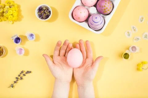 Child hands decorate Easter eggs on yellow background. Happy easter concept. Stock Photos