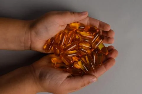 Child hands holding fish oil capsules on white background. Children's health Stock Photos