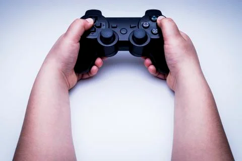 Child hands playing with the black remote of a console. Stock Photos