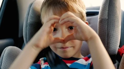 Child hands showing heart while sitting in car seat Stock Footage 77730883