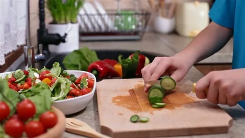 Child hands slicing a cucumber for a vegetables salad Stock Footage 80449392