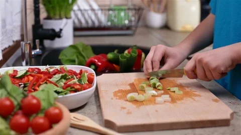 Child hands slicing spring onion for a vegetables salad Stock Footage 80241857