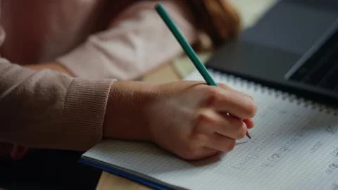 Child hands solving problems in notebook. Thoughtful girl studying at home. Stock Photos
