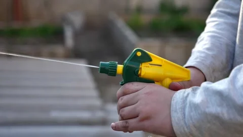 Child hands spraying water with a plastic spray bottle in the garden Stock Footage 339979370