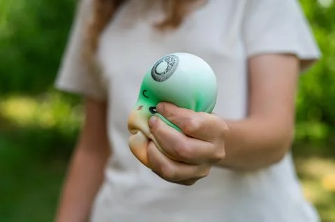 Child hands squeezing a soft dumpling squishy toy outdoors Stock Photos