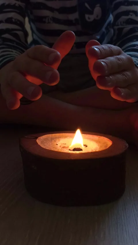 Child hands warming over a small candle flame. Stock Footage 343419991
