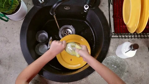 Child hands washing a drinking glass with sponge - top view Stock Footage 80449367