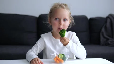 Child happily eats healthy broccoli and other vegetables. Plate is filled with Stock Footage 276136618
