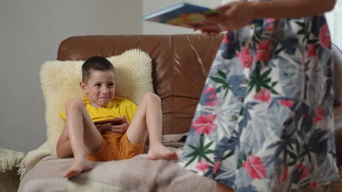A Child Happily Enjoying Screen Time on a Couch While a Parent Stays Nearby Stock Footage 305263229